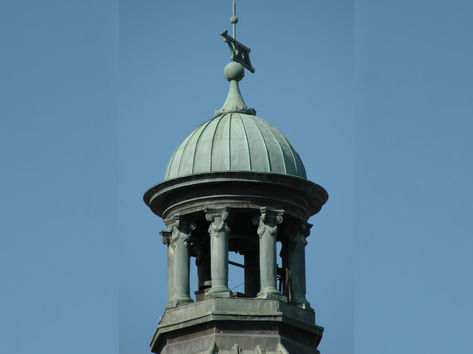 Before restoration shot of courthouse dome and cupola with patinaed copper finish against a clear sky.