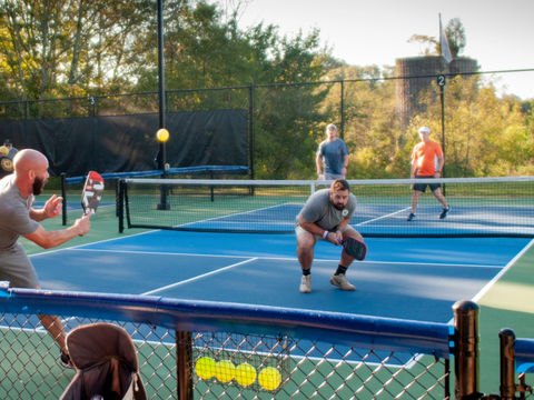 Close-up of players rallying during pickleball game on blue court surface