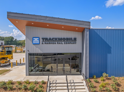 Headley Construction-built Trackmobile manufacturing facility featuring a modern industrial building with metal panel exterior, glass entry, landscaped site work, and rail equipment on display at the Georgia location.