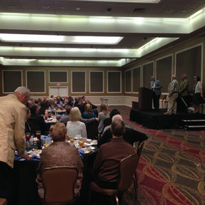 Group of people sitting at round tables.