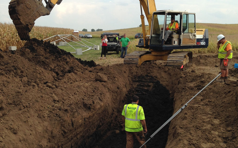 Excavator near a man in a large trench