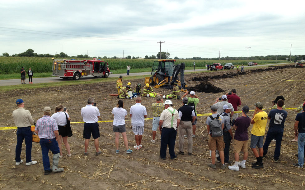 Group of people in a field watching a backhoe