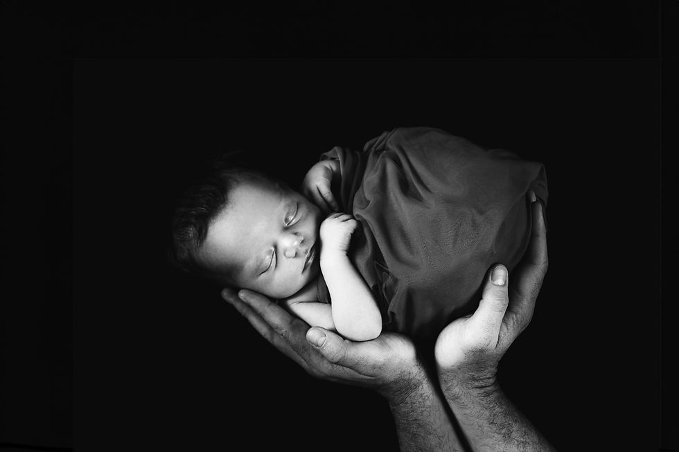Sleeping newborn held in hands from a photography session