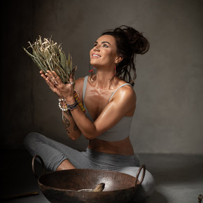 Agi Jensen pozuje w stylizacji do jogi, w ręce trzyma trawy