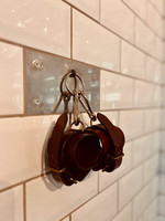 Leather cuffs hanging on hook on tile wall