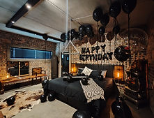 Dark guesthouse bedroom with 'Happy Birthday' decor and black balloons