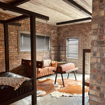 Rustic bedroom with exposed brick walls, four-poster bed, and leather couches