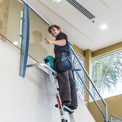Window cleaner on ladder giving a thumbs up