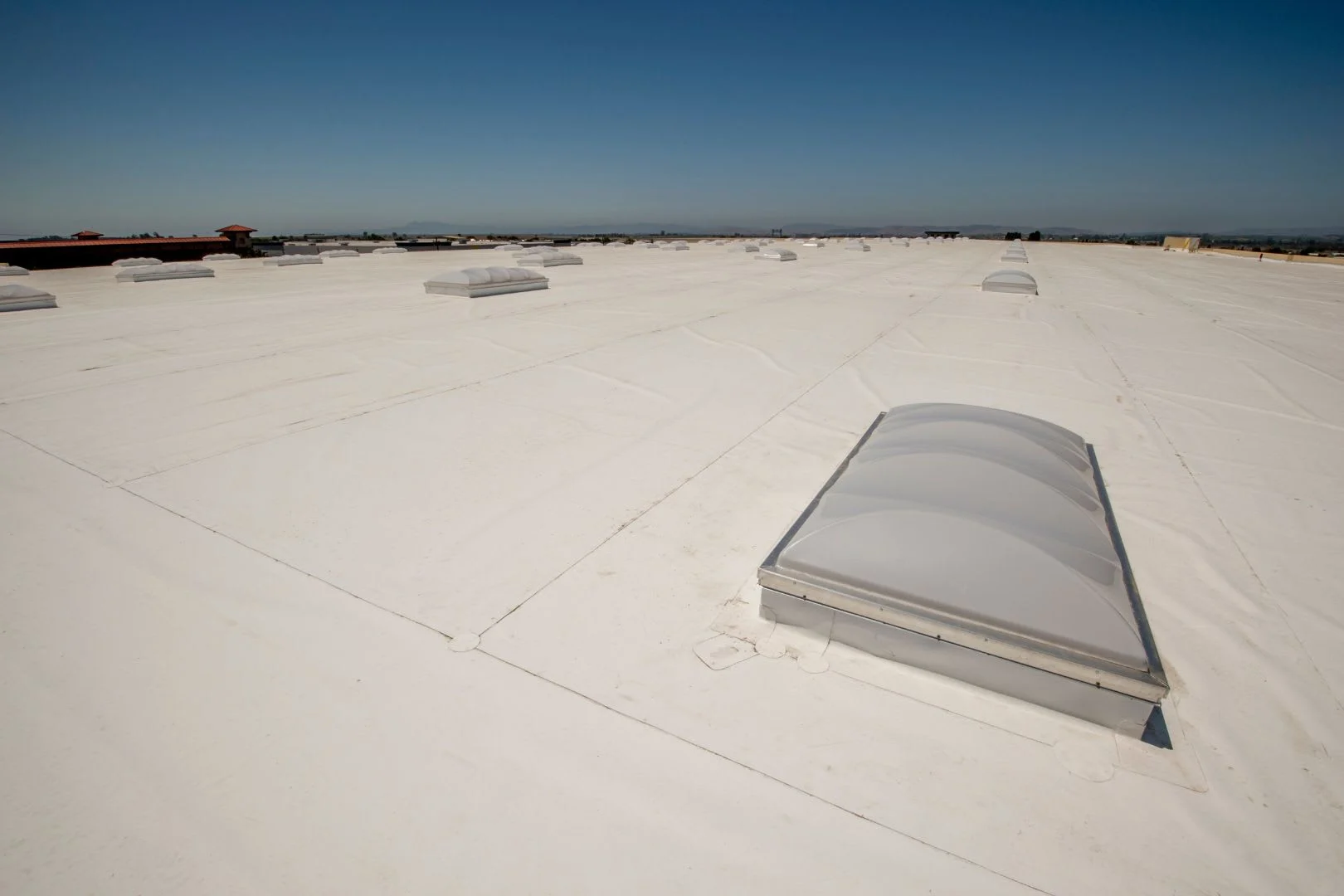 Close-up of a commercial PVC roofing system with white, heat-welded seams for waterproofing and UV resistance.