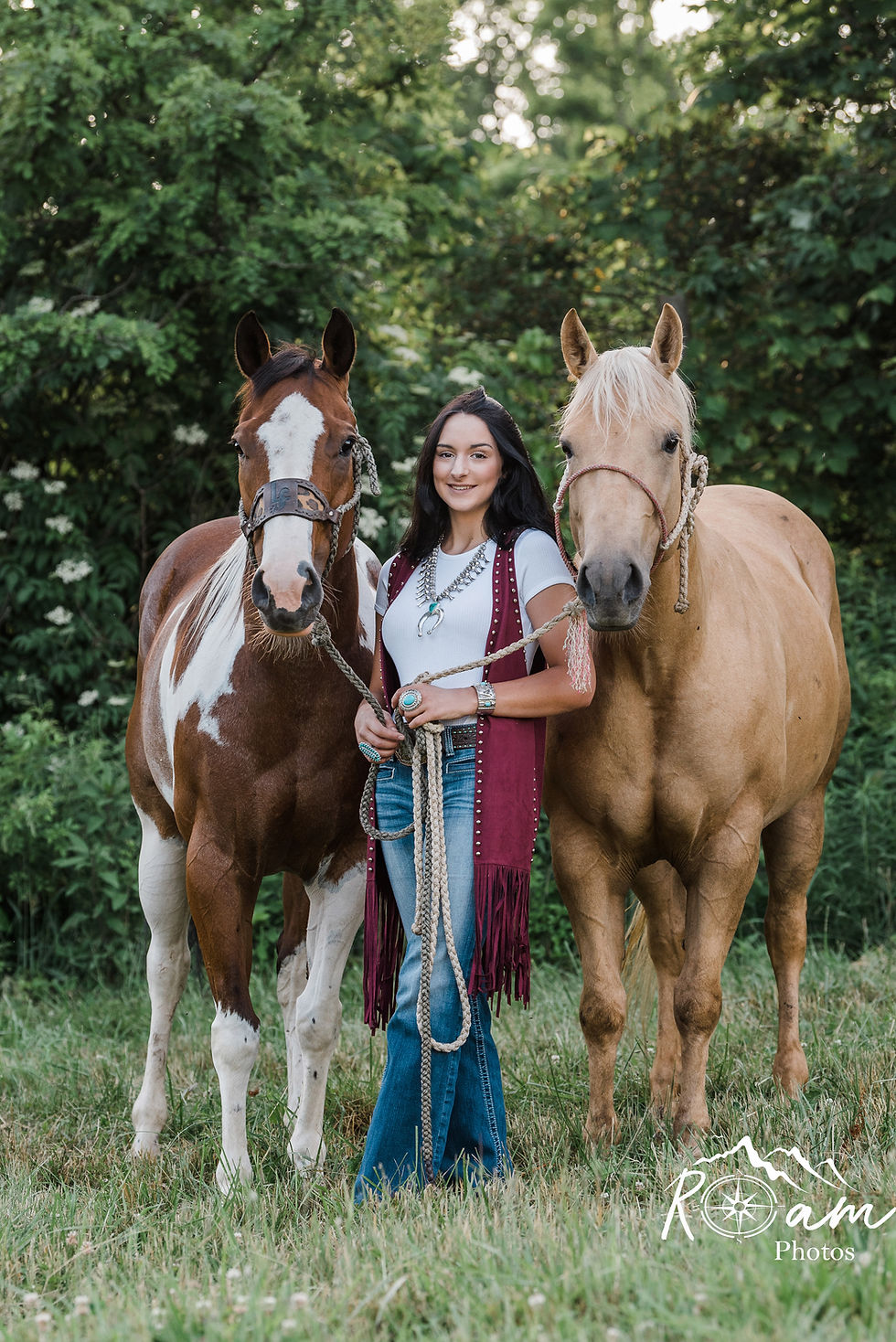 Cowgirl holding two horses.