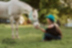 Cowgirl sitting in grass with beautiful horse