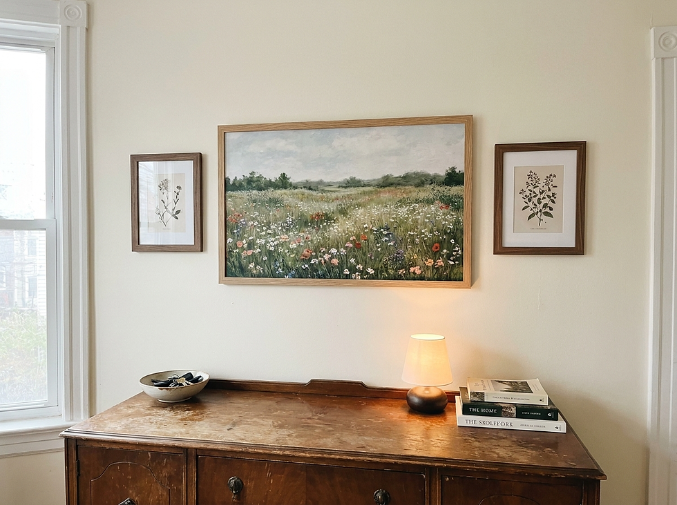 Real apartment gallery wall with a wide floral meadow print and smaller botanical companion artworks