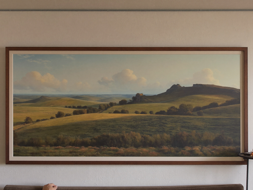 Wide framed landscape being positioned directly above a sofa with calm spacing