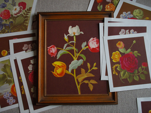 Floral art prints with white paper borders arranged around a wooden frame on linen.