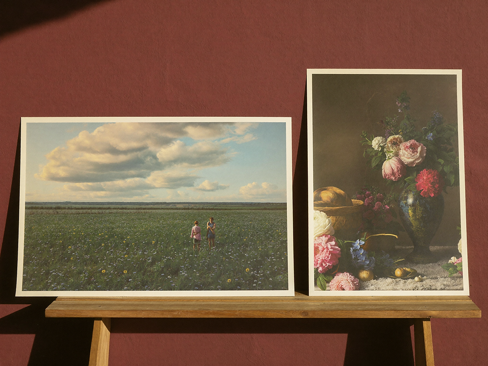 Horizontal landscape and vertical floral prints leaning side by side in an art studio.