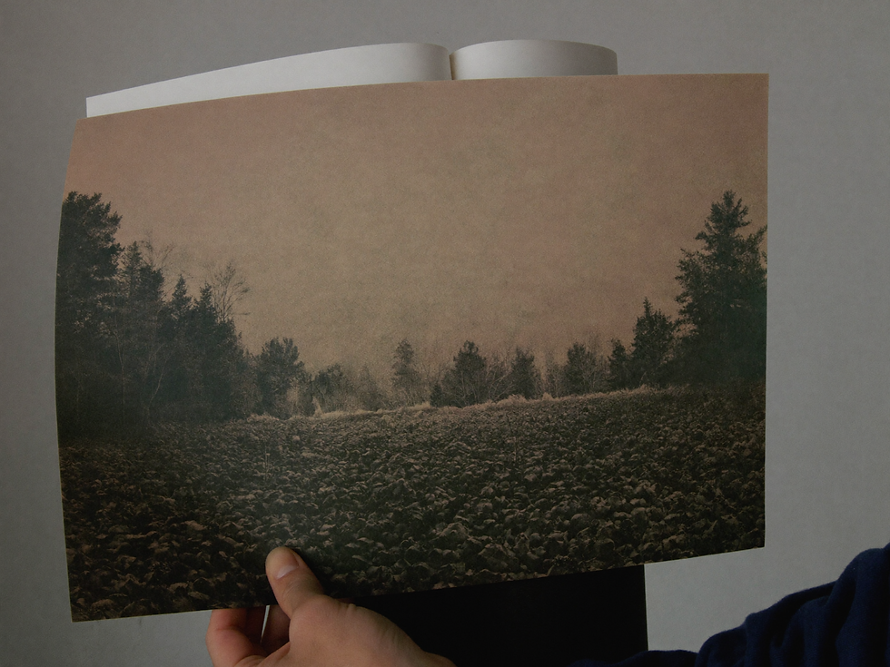 Hands lifting a large misty landscape print from an archival portfolio