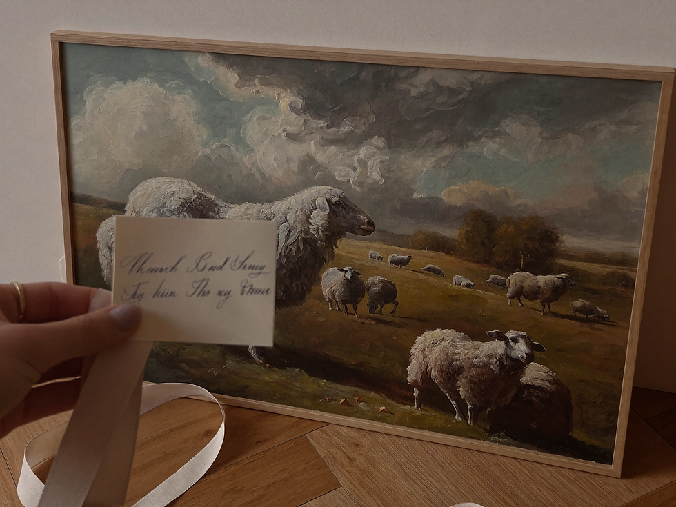 Gift card and linen ribbon placed beside a framed pastoral landscape painting.