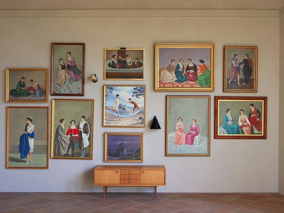 Gallery arrangement of vintage oil paintings above a sideboard