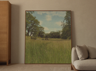 Warm neutral living room centered on a large vintage meadow landscape painting.