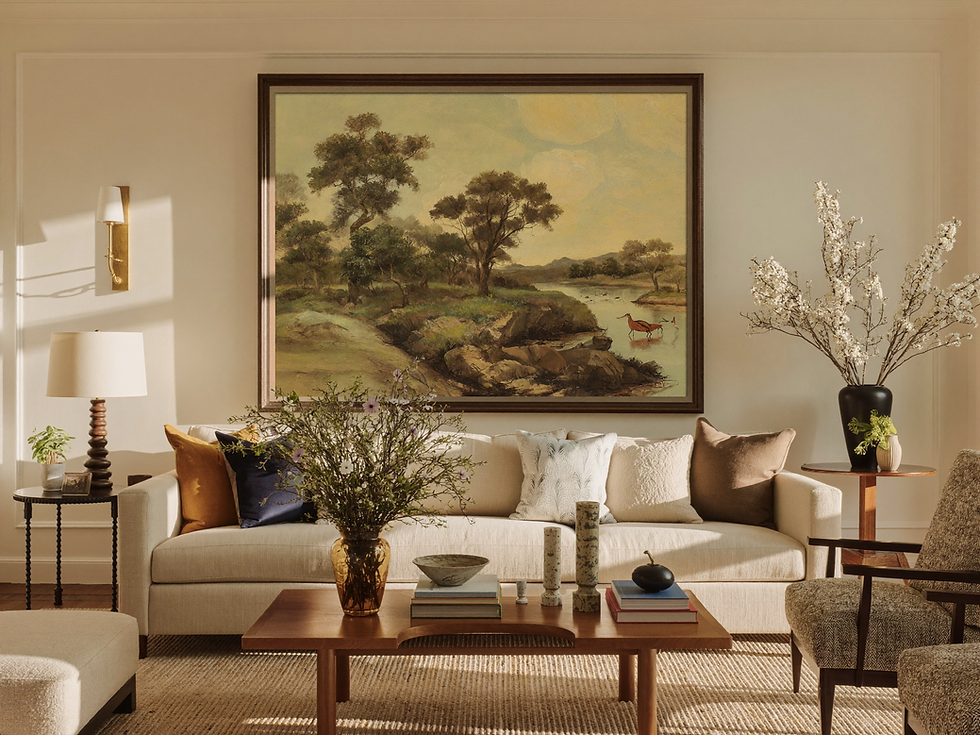 Framed landscape art above a sofa in a sunlit living room
