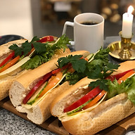 Fyra smörgåsar med färska grönsaker, ost och skinka bredvid en kaffe kopp och ett ljus