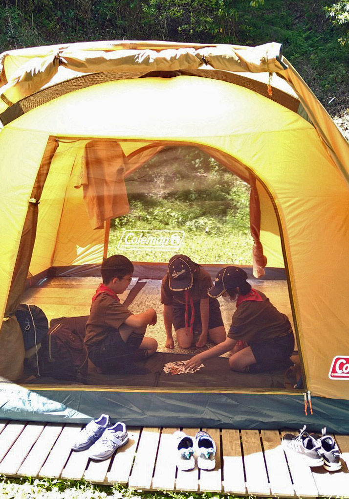 3人のカブスカウトがテントの中に入ってトランプをしている様子