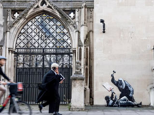  A judge in a wig walks in front of a Banksy painting.