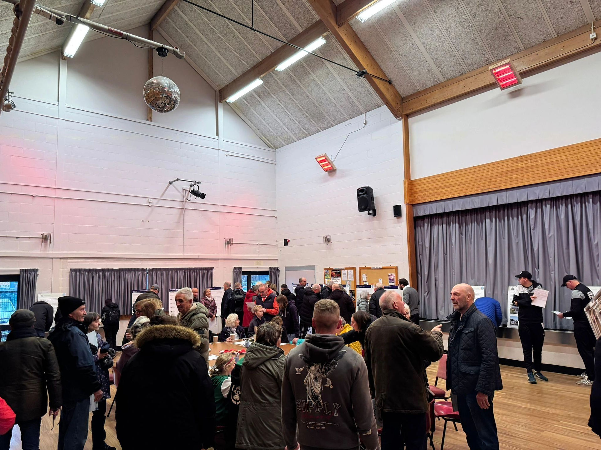 Community takes part in consultation event, they gather around tables in a hall