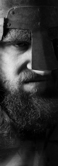 Homme barbu portant une tenue historique, photographié en noir et blanc.