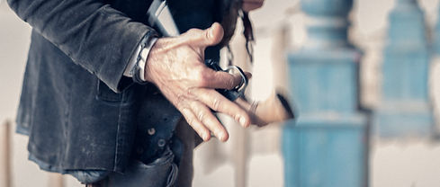 Gros plan sur les mains d’un comédien faisant tourner un revolver avant de le ranger dans son holster, dans une ambiance cinématographique inspirée du western.