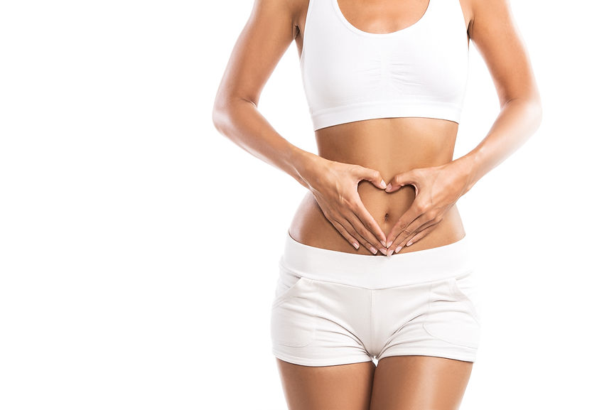 Fit young woman holding a heart over her abdomen, isolated on white background.jpg