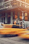 Blurred yellow taxi speeding past a city office building
