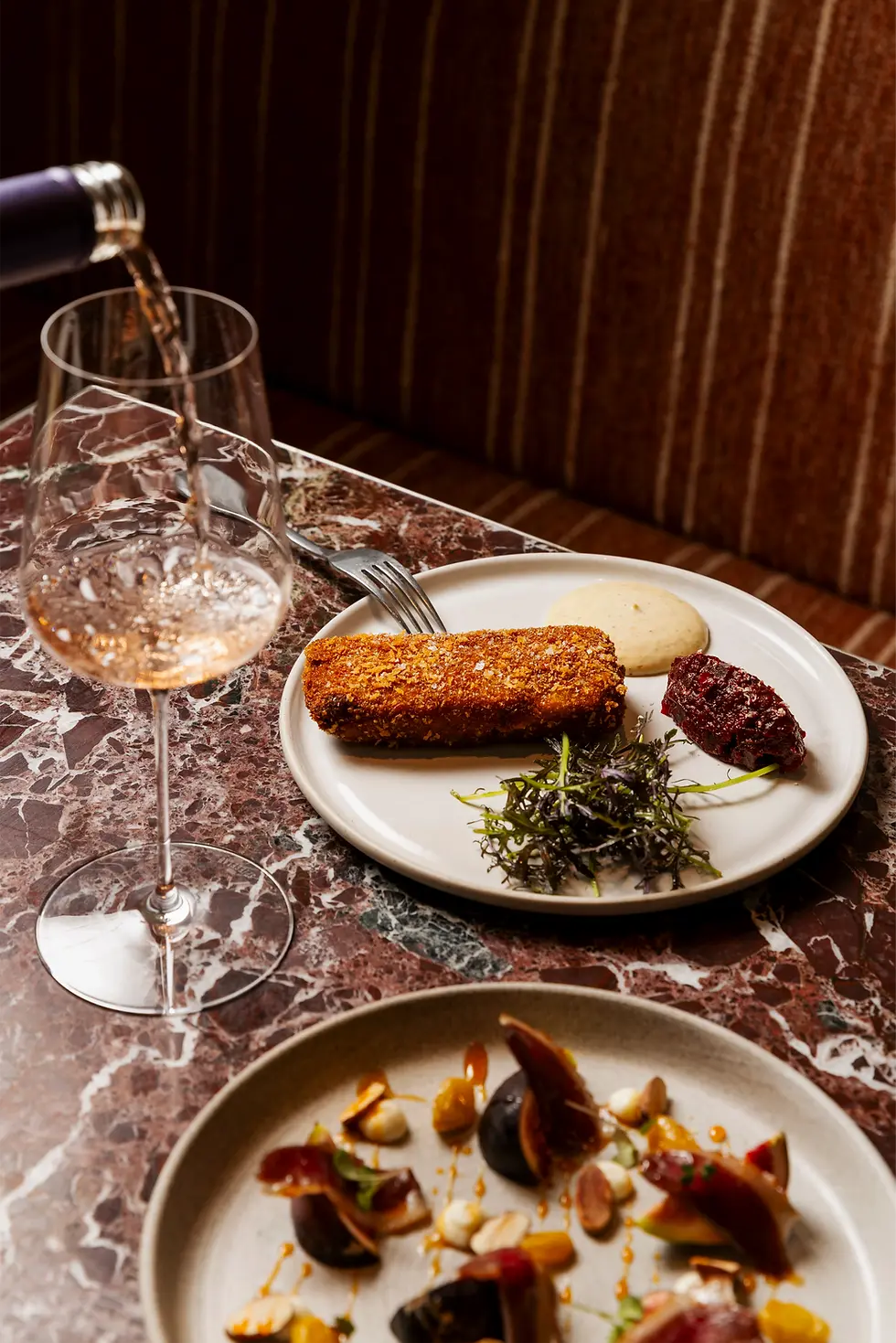 Two plates on the table with a glass of wine at Bistro X Fitzroy