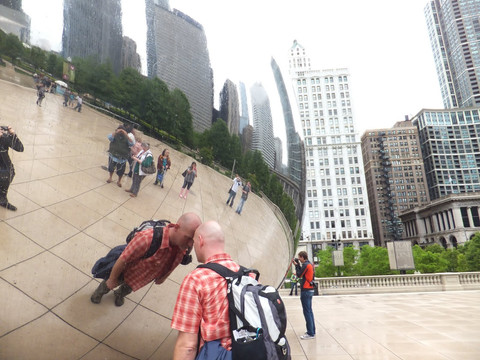 Tourists taking photos of Chicago's cityscape reflected in Cloud Gate sculpture