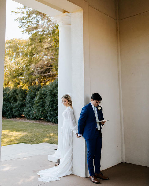 bride and groom holding hands with a wall separating them