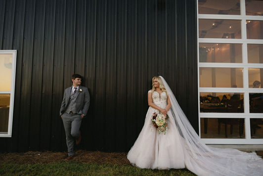 bride and groom standing on the side of the barn