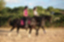 two girls hacking horses in countryside