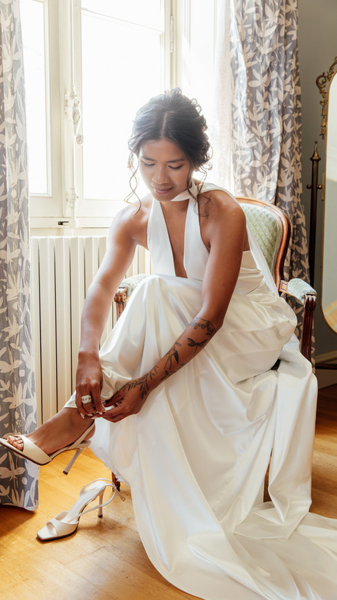 La mariée mettant ses chaussures assise sur une chaise