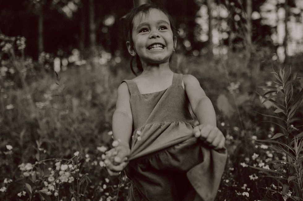 Little girl holding her dress and smiling at a summer family photo session