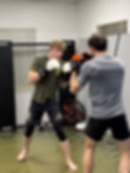 A boxer practicing punches on a heavy bag in a gym, focusing on technique and strength during training.