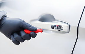 The thief uses a screwdriver Stealing a car at the door handle. The vehicle insurance conc