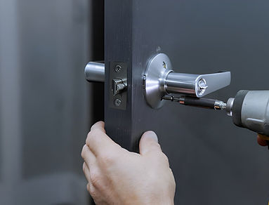 Installing lock handles on room doors with screwdriver by a carpenter stock photo.jpg