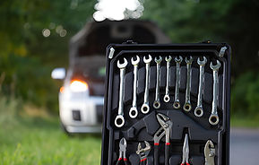 Wrenches and tools in a case against the background of a broken car.jpg