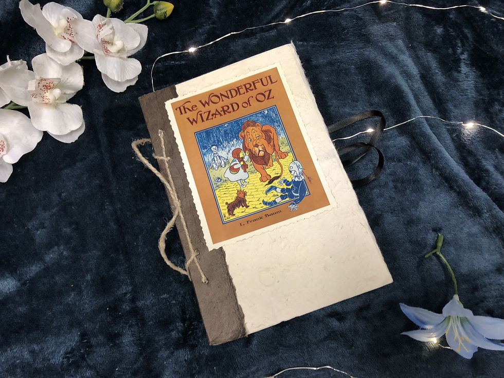 Thumbnail: A Rustic copy of Wizard of Oz, in speckled white with brown spine, tied together with a hemp cord at the spine.