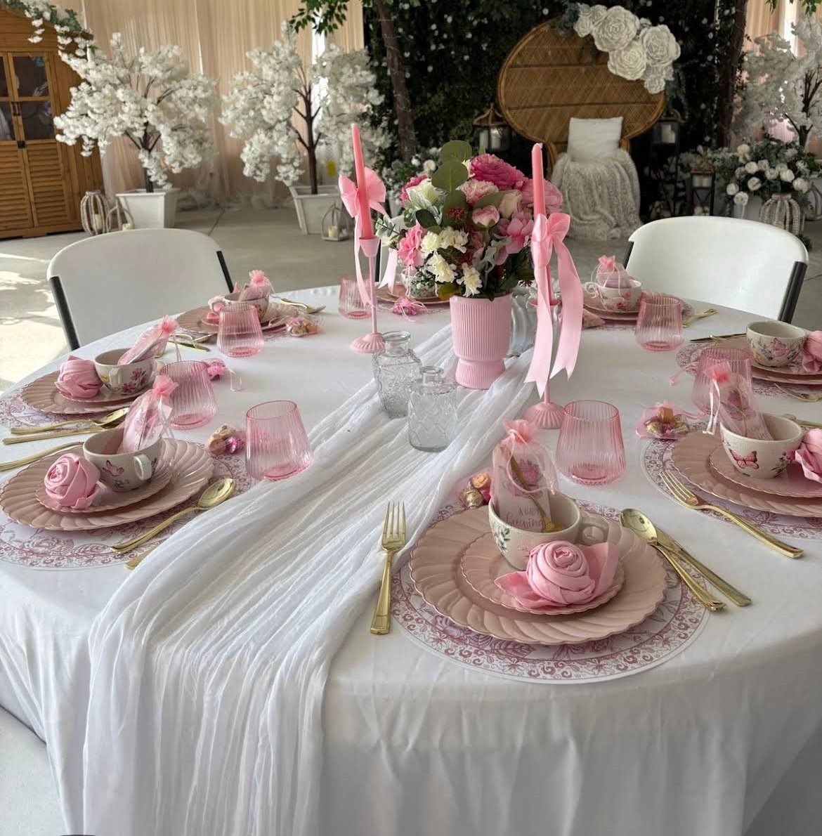 Wide-angle view of a decorated baby shower table with candles, florals, and soft table linens.