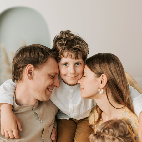 Un enfant réalise des exercices myofonctionnels à la maison, accompagné de ses parents. Ceux-ci l’encouragent avec bienveillance et le soutiennent dans sa thérapie en répétant les exercices avec lui.