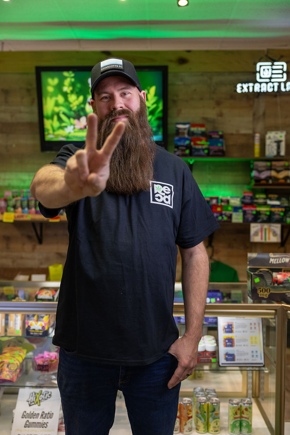 Eye-level view of Will standing inside The Rec Dispensary store with shelves of products behind him