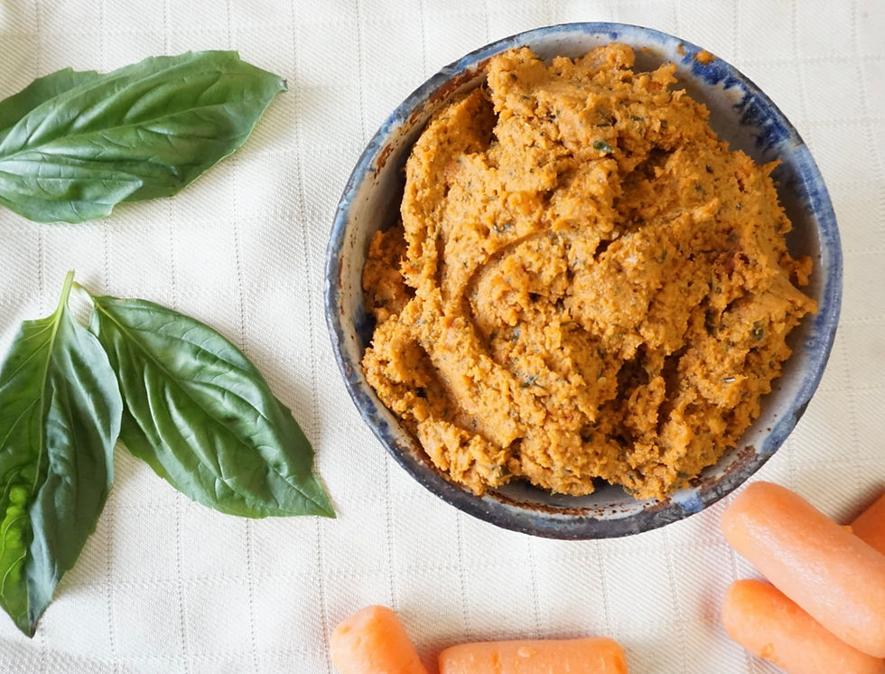bowl of sun-dried tomato hummus with basil and carrots