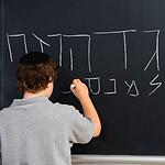 Boy Writing Hebrew Letters on Blackboard