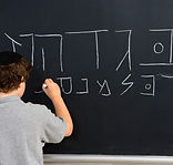 Boy Writing Hebrew Letters on Blackboard